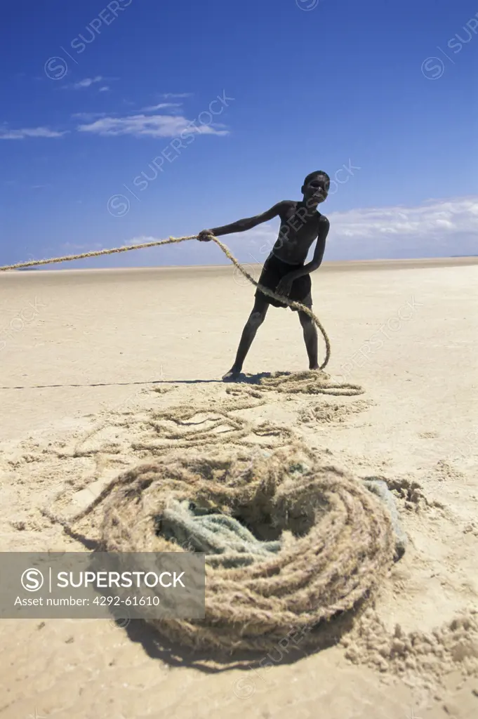 Boy helping the fishermen pulling up the net to the beach in Benguerra, Africa, Mozambique