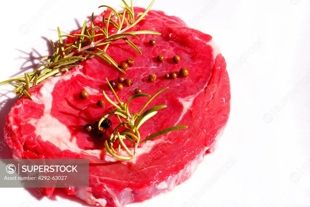 Raw beef steak with rosemary and peppercorns