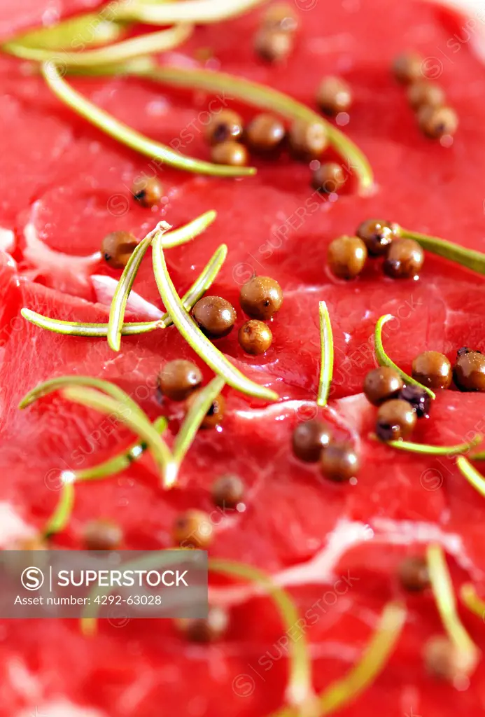 Raw beef steak with rosemary and peppercorns