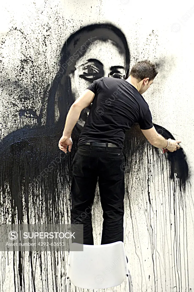 Young man spray painting on wall