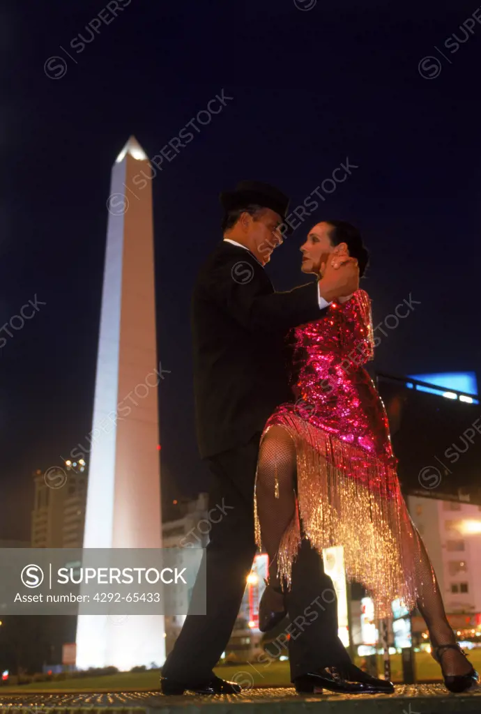 Couple standing near the Obelisk on Avenida 9 de Julio in Buenos Aires at night