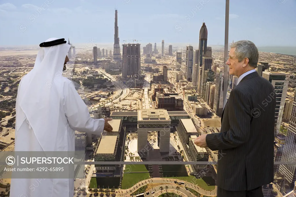Dubai, United Arab Emirates. Businessmen standing at office window