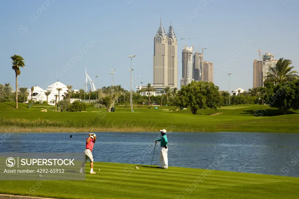 United Arab Emirates, Dubai, Golfers tee off on Emirates Golf Course. Club House on the left and new buildings on Sheikh Zayed Road.
