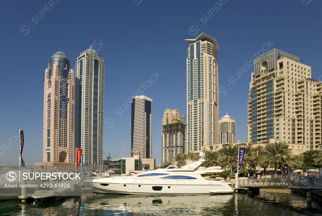 United Arab Emirates, Dubai, Luxury motor cruisers moored at Dubai Marina with apartment tower blocks in the background.