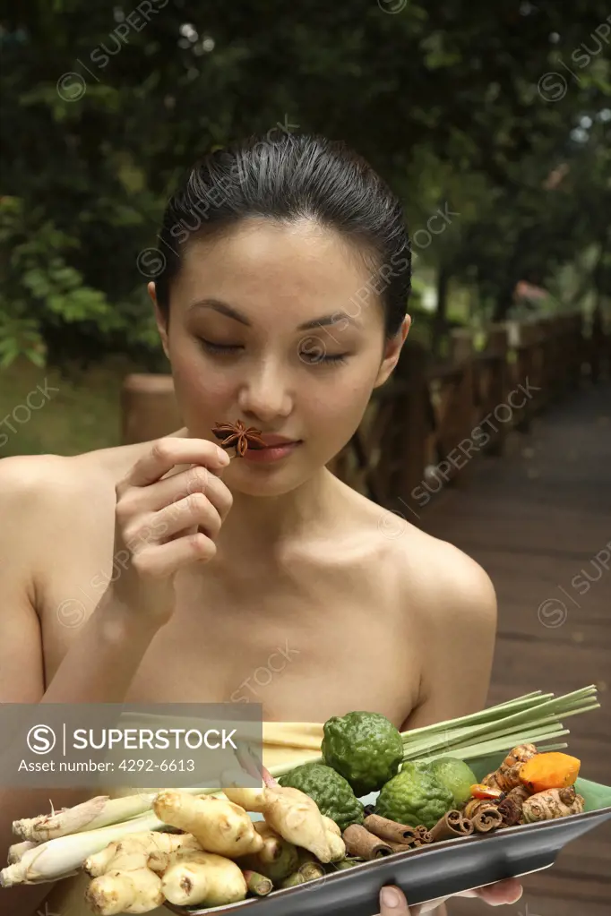 Girl holding a tray full of ingredients for Jamu - Indonesian Herbal Elixir