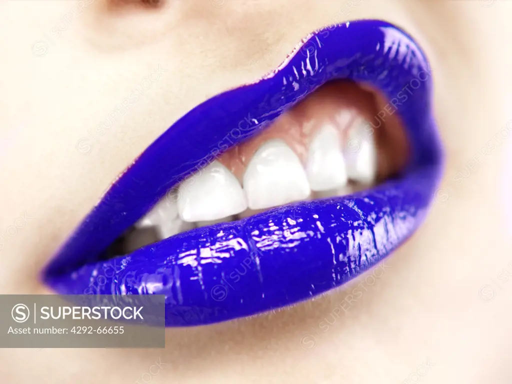 Close up of woman's mouth wearing purple lipstick, making faces