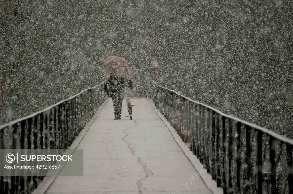 Man walking on bridge under the snow