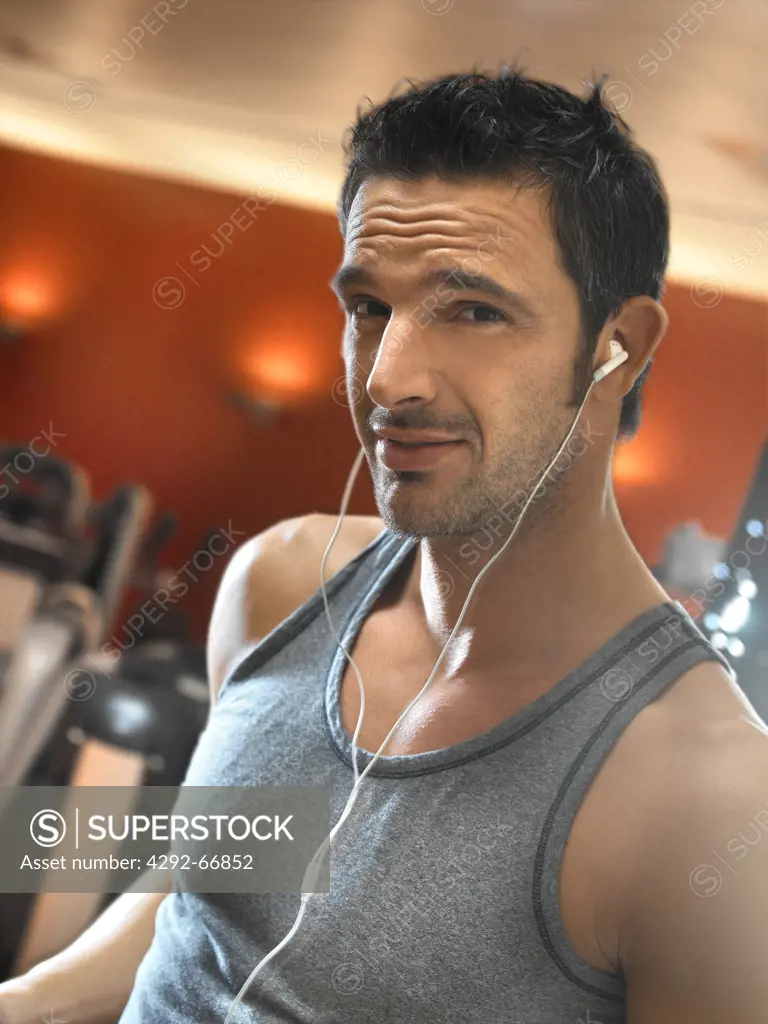 Portrait of man listening to music while exercising in gym