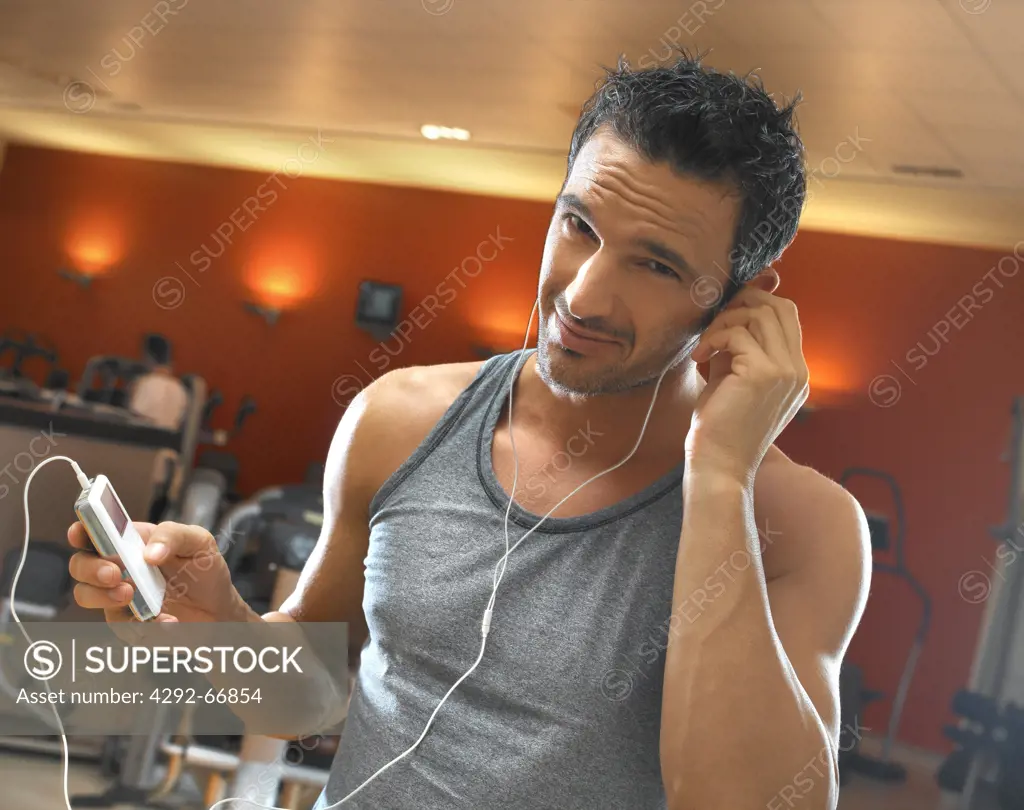 Man in gym listening to music with mp3 player while exercising