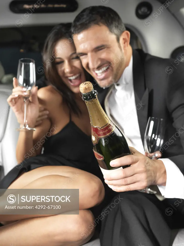 Couple in limousine celebrating with champagne