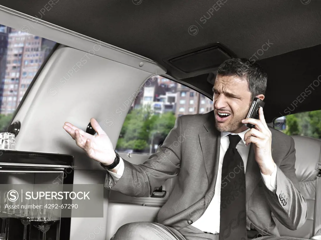 Businessman on mobile sitting in the back seat of a limousine