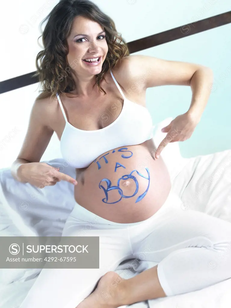 Pregnant woman with it's a boy written on her belly