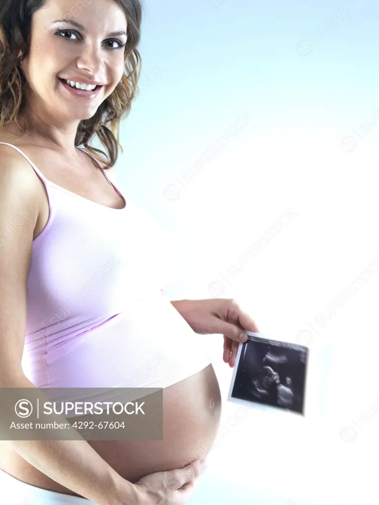 Pregnant woman holding ultrasound photograph of her baby