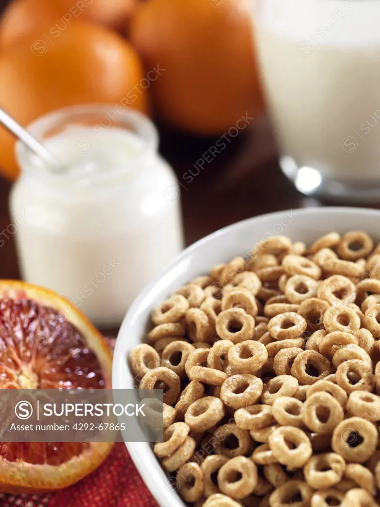 Bowl of cereals, yogurt jar and orannges