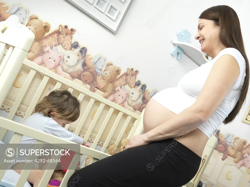 Pregnant mother playing with son in the crib