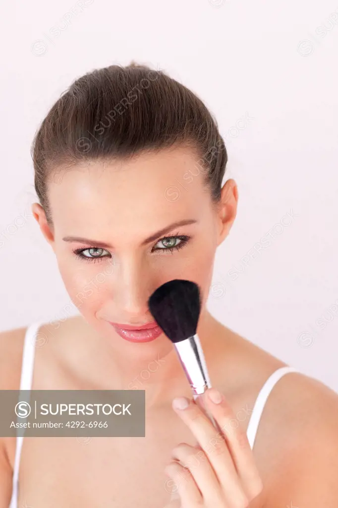 Portrait of woman applying make up with brush