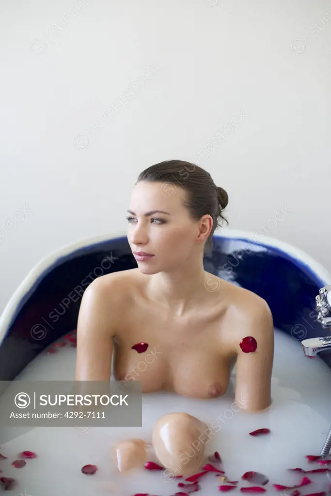 Woman relaxing in tub filled with rose petals