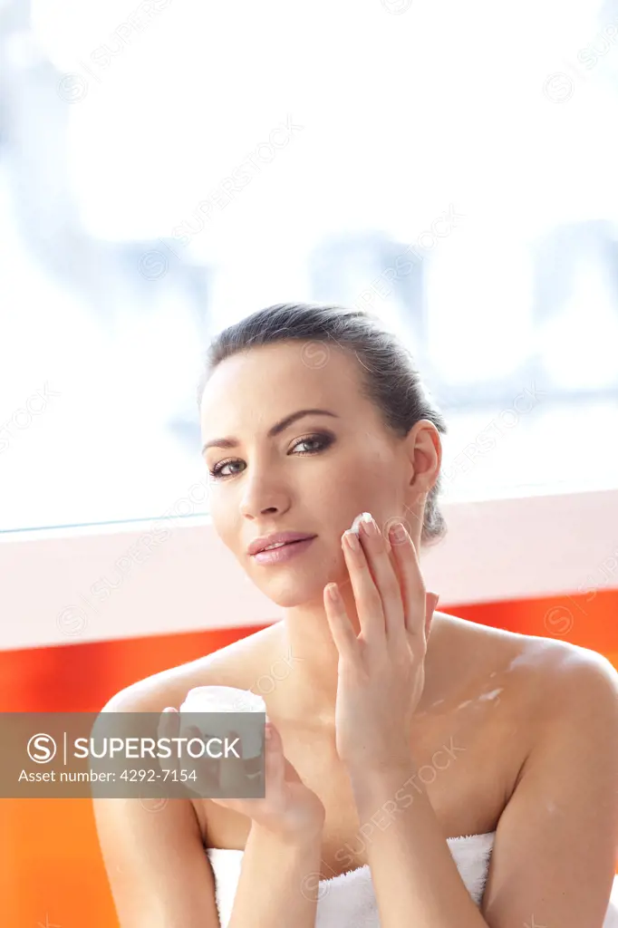 Young woman applying moisturizer