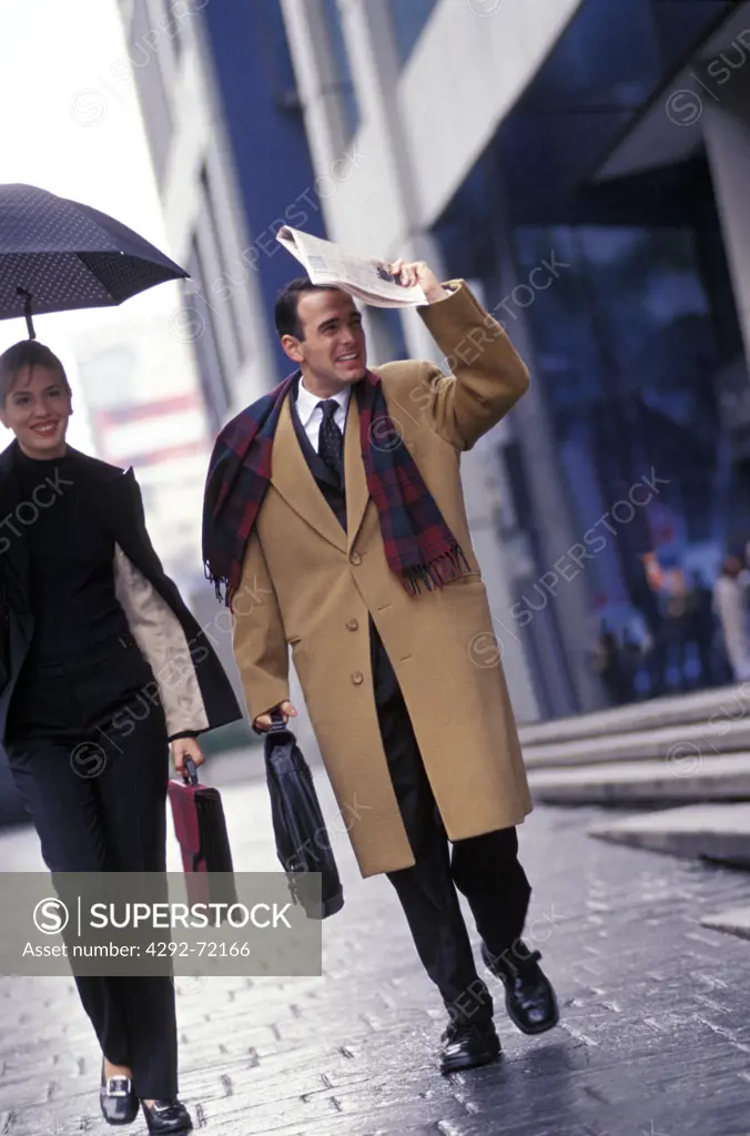 Businessman and woman walking under the rain
