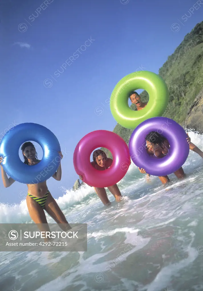 Friends at seaside, playing with inflatable rings