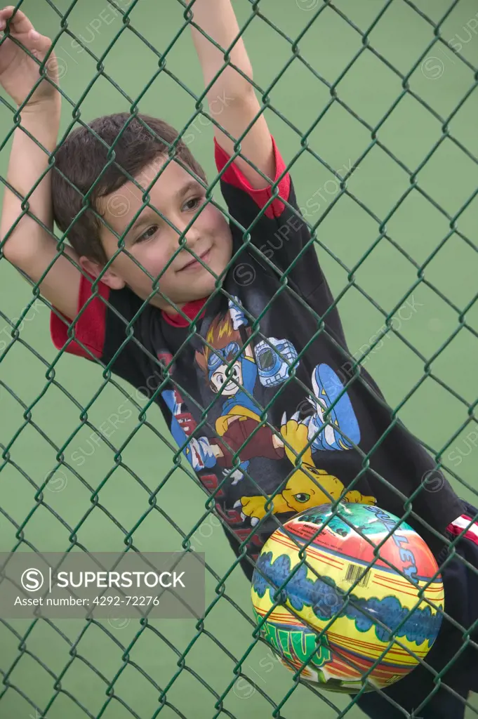 Boy leaning against chainlink fence