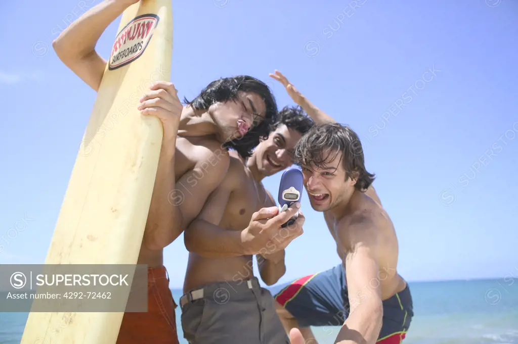 Group of friends taking picture with mobile on beach
