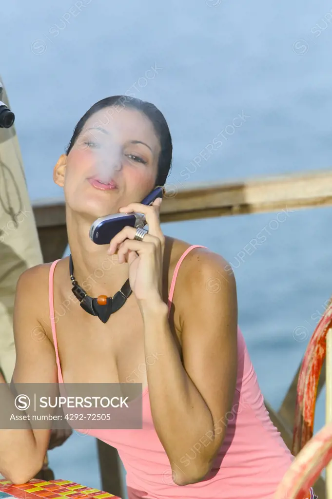 Young woman smoking cigarette while phoning outdoors