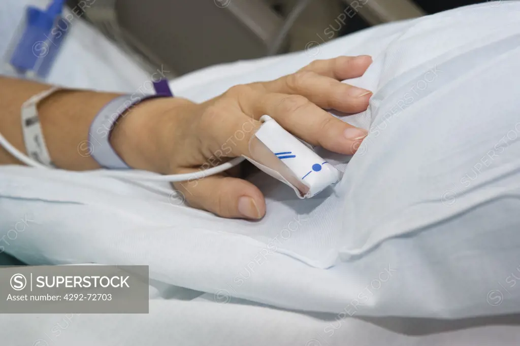 Hand of woman with pulse sensor on finger in hospital