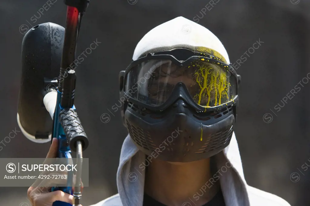 Boy with paintball gun and mask splashed with paint