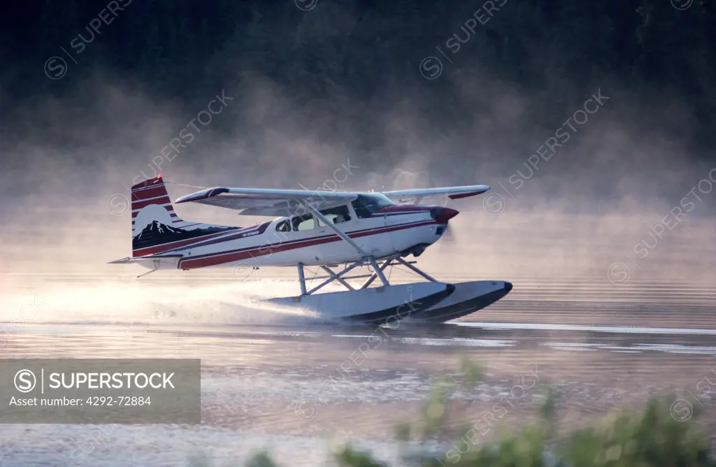 Bush plane landing on misty lake