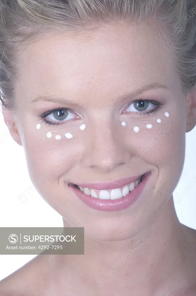 Young woman with moisturizer under eyes