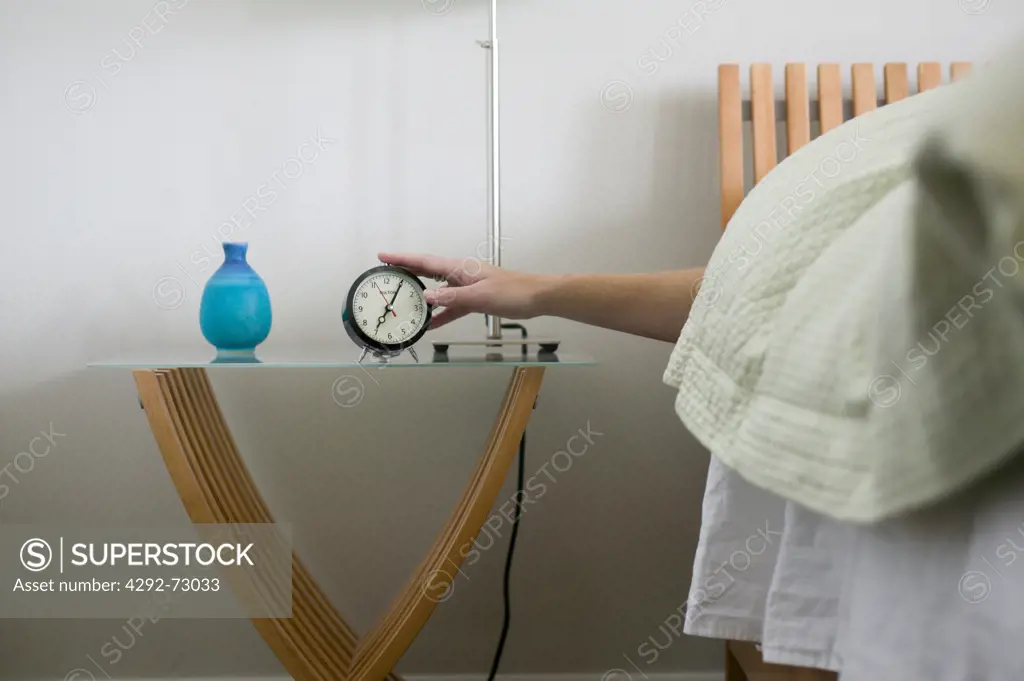 Woman's hand reaching out for alarm clock