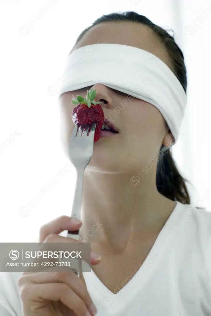 Blindfolded woman eating a strawberry