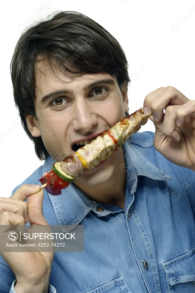Man eating meat skewer