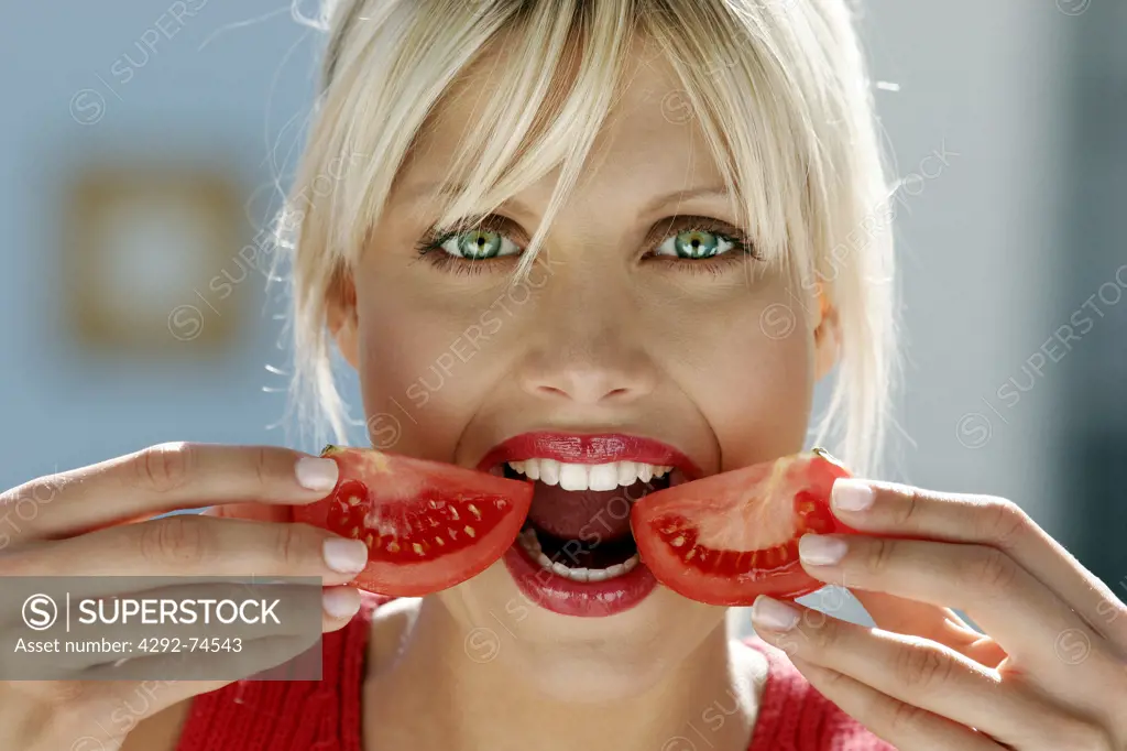 Woman eating a slice of tomato