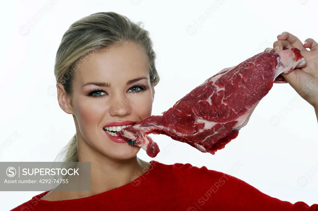 Woman biting into chunk of raw meat