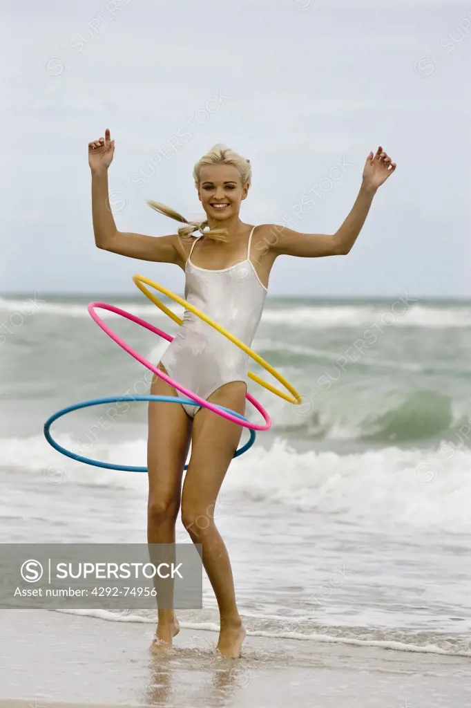 Woman at seasisde playing with hoola hoops