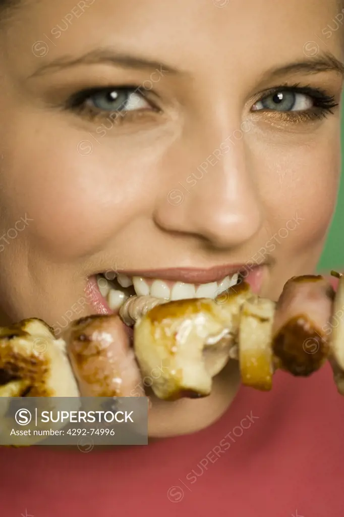 Close up of woman's face eating a meat skewer