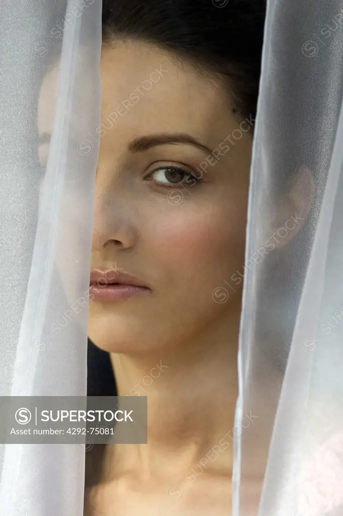 Woman's face behind curtain