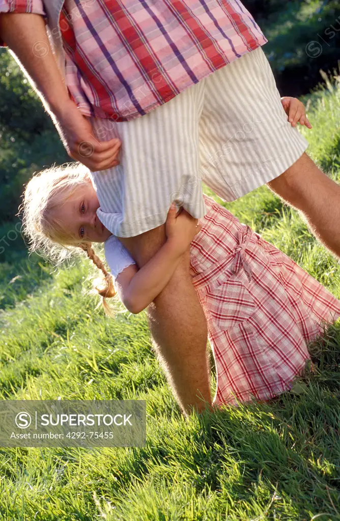 Girl hiding behind father's legs