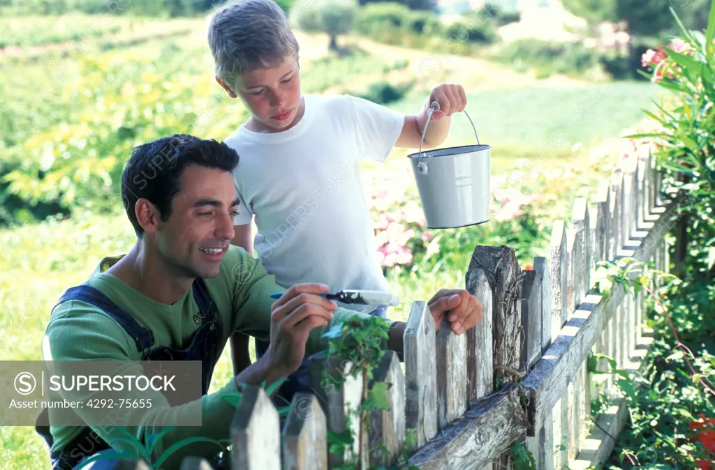 Man painting fence with his son
