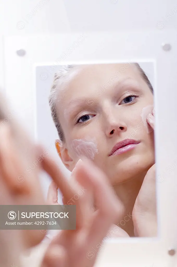 Young woman applying moisturizer