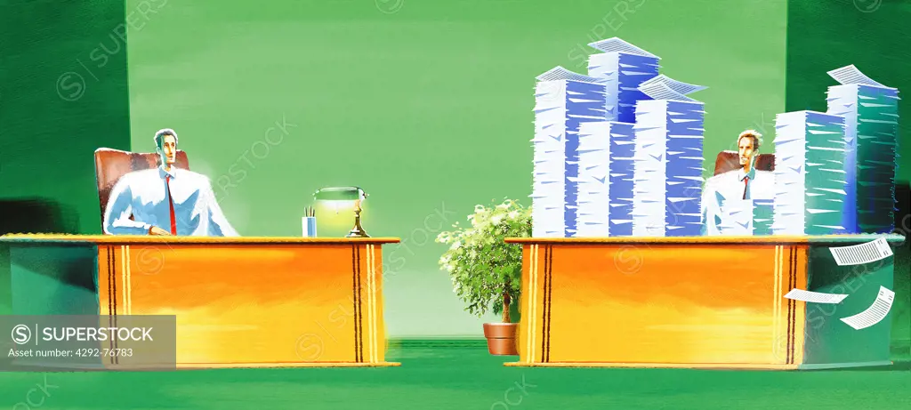 Employee  in office with a stack of paperworks in front of his colleague with empty desk
