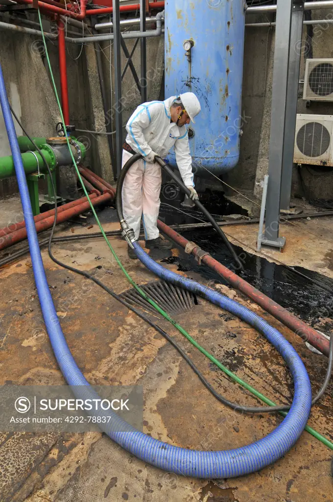 Man cleaning oil contaminated storage tank