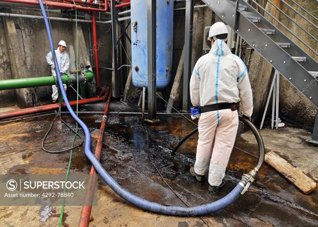 Man cleaning oil contaminated storage tank
