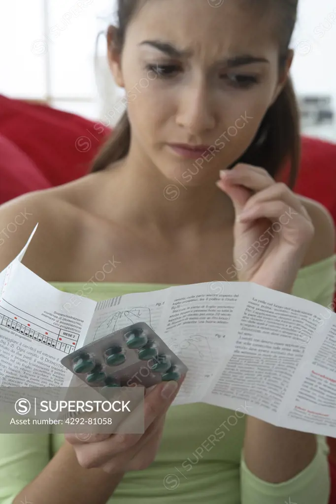 Woman holding blister pack pills and reading medical leaflet