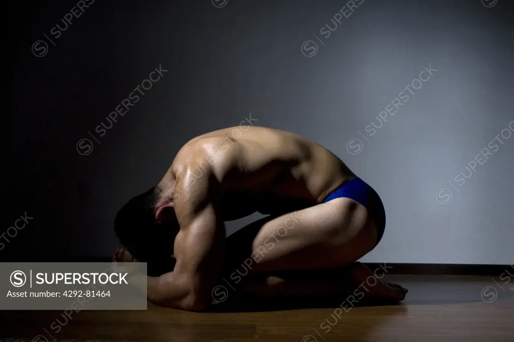 Studio shot of a man, curled up