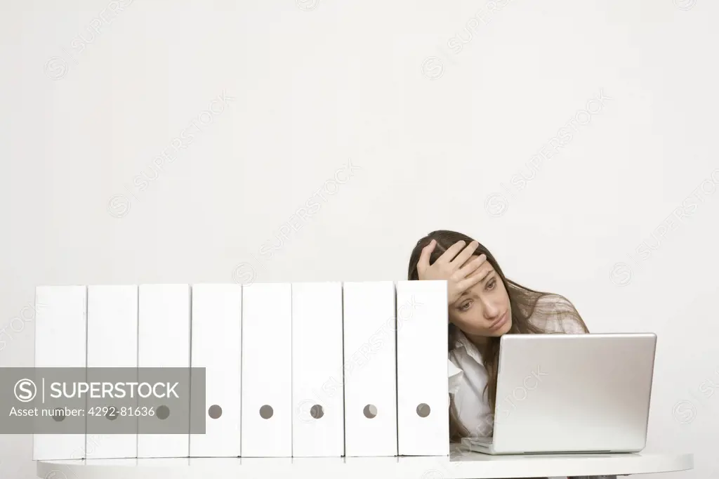 Tired woman in office in front of laptop