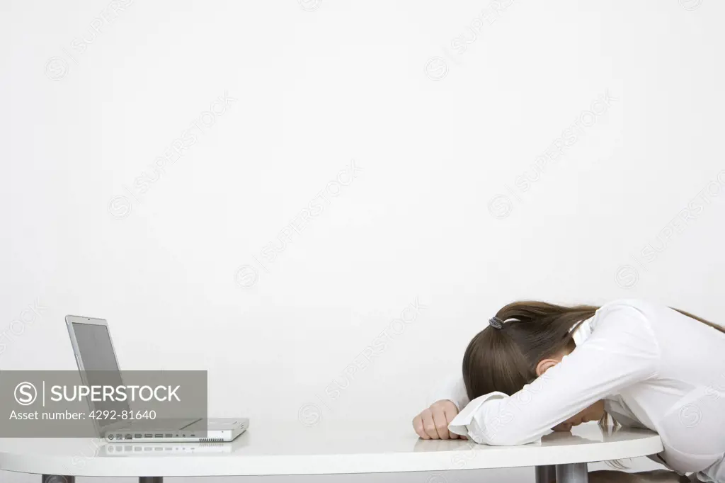 Tired woman in office sleeping at her desk