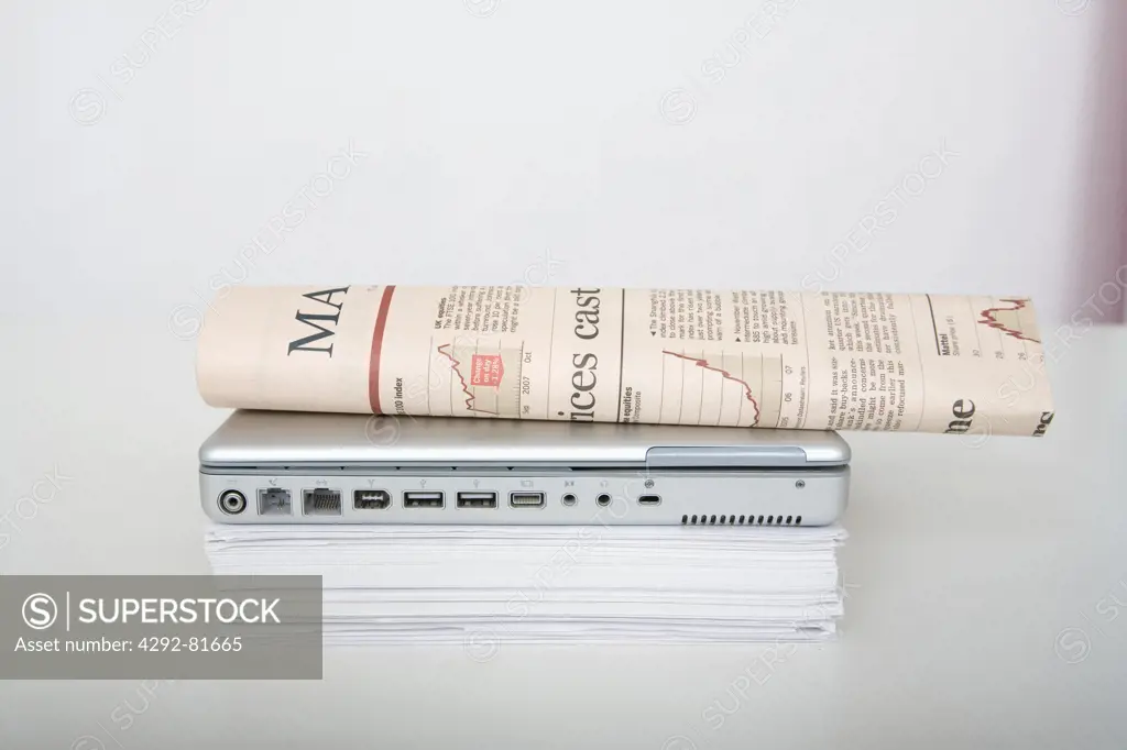 Close-up of a newspaper, laptop and paperworks on desk